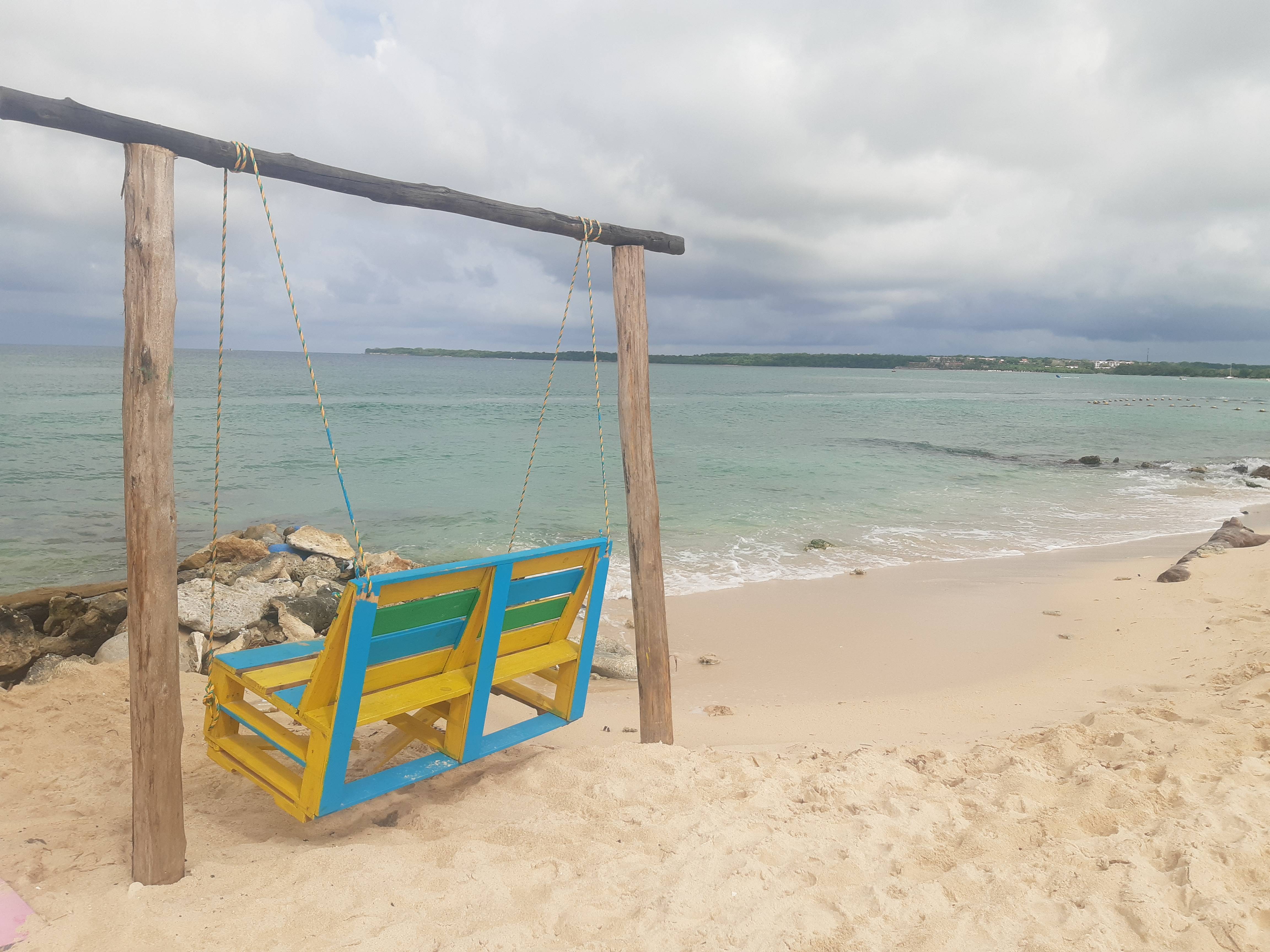 Playa con letrero de madera señalando destinos